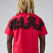 Person wearing a red t-shirt with black graphics on the back against a gray background