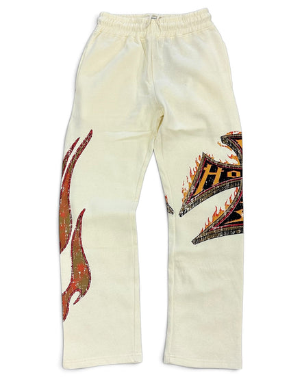 Off-white sweatpants featuring a large red and green flame graphic on the right leg and a black, orange, and yellow tribal-style graphic on the left leg, displayed flat against a white background.