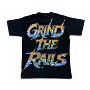 A black short-sleeve t-shirt with a large graphic on the back reading 'GRIND THE RAILS' in stylized metallic lettering with a blue, purple, and orange tie-dye pattern, shown on a plain white background.