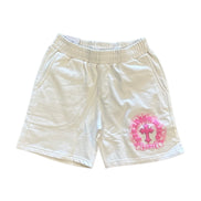 Beige shorts with pink floral design and cross on a white background