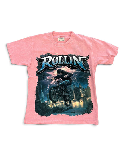 A pink short-sleeve graphic t-shirt featuring a large front print of a mountain biker with the word 'ROLLIN' in stylized blue and white lettering above, set against a plain white background.