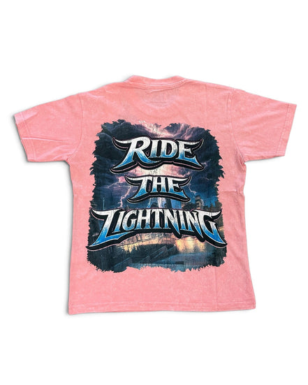 A pink short-sleeve t-shirt with a large graphic print on the back featuring the text 'RIDE THE LIGHTNING' in stylized blue and white lettering over a dark stormy background.