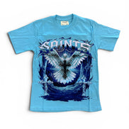 A light blue short-sleeve graphic t-shirt featuring a large front print of a white angel with wings and a cross, with the word 'SAINTS' in stylized white lettering above, on a white background.