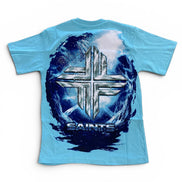 A light blue short-sleeve t-shirt with a large back graphic featuring a metallic silver cross over a dark blue and white circular design with the word 'SAINTS' underneath.