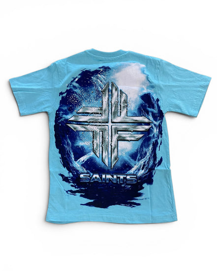 A light blue short-sleeve t-shirt with a large back graphic featuring a metallic silver cross over a dark blue and white circular design with the word 'SAINTS' underneath.