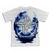 A white short-sleeve t-shirt with a large graphic on the back featuring a metallic silver cross inside a swirling blue and white circular design, with the word 'SAINTS' printed below.