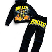 A two-piece kids' tracksuit set consisting of a black cropped hoodie and matching sweatpants, both featuring a large yellow 'BALLER' graphic and a basketball player illustration on the front.