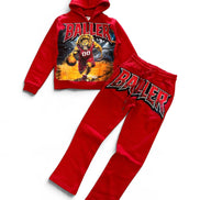 A two-piece kids' sweatshirt and jogger set in bright red, featuring a graphic hoodie with a basketball player print and the word 'BALLER' on the front, paired with matching joggers that have a large 'BALLER' graphic on the thigh.