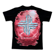 A black short-sleeve t-shirt featuring a large graphic print on the front. The design shows a metallic silver cross symbol layered over a pink and red textured circular background, with the word 'SAINTS' printed in red below.