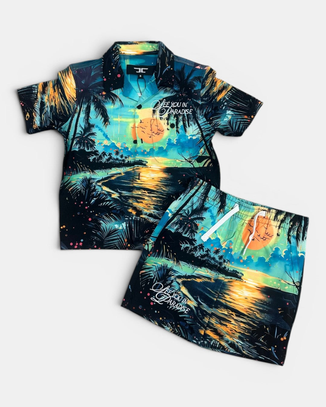 Tropical-themed shirt and shorts set with palm trees and sunset design on a white background