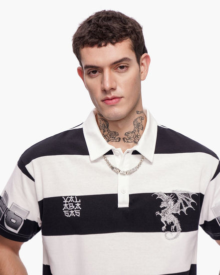 Man wearing a black and white striped polo shirt with dragon design on a white background