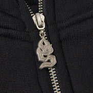 Close-up of a black zipper with a silver flame pendant on a black background