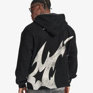 Person wearing a black hoodie with flame design on the back against a white background