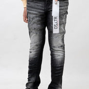Person wearing black distressed jeans with a brand tag, standing against a white background