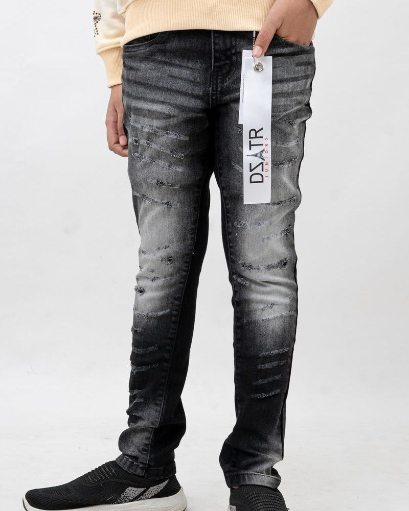 Person wearing black distressed jeans with a brand tag, standing against a white background
