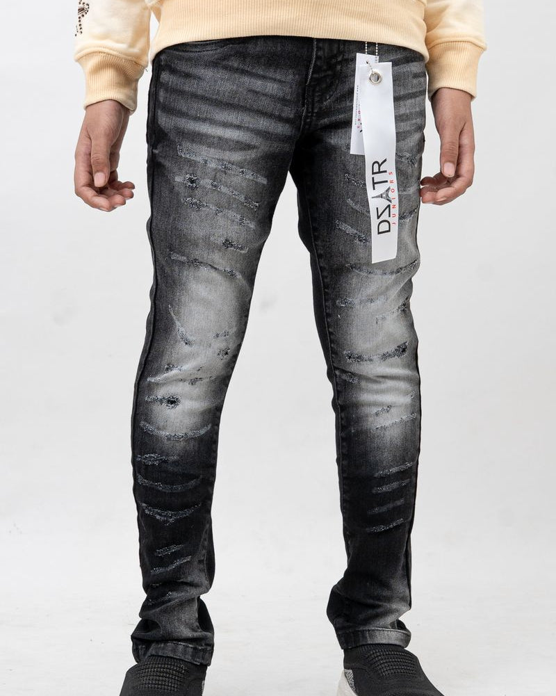 Person wearing black distressed jeans with a visible brand label on a white background