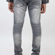 Person wearing gray jeans and a denim jacket on a white background