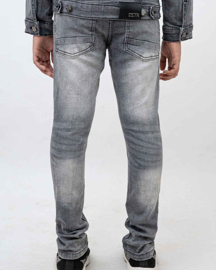 Person wearing gray jeans and a denim jacket on a white background