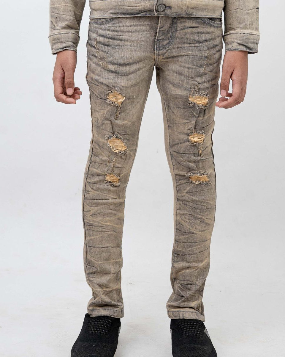 Distressed beige jeans worn by a person on a white background