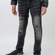 Person wearing black distressed jeans and a dark jacket on a white background