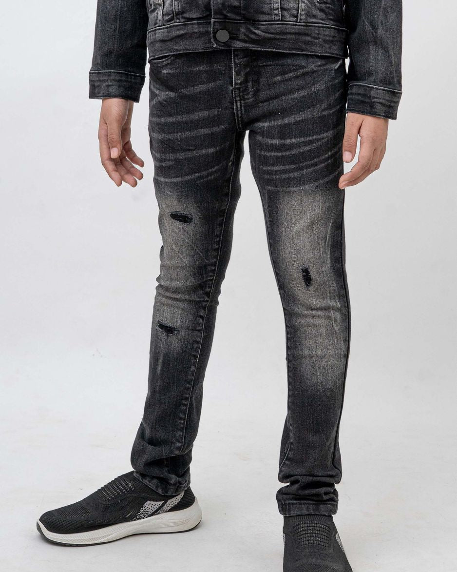 Person wearing black distressed jeans and a dark jacket on a white background