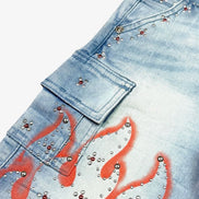 Blue jeans with red flame designs and silver studs on a white background