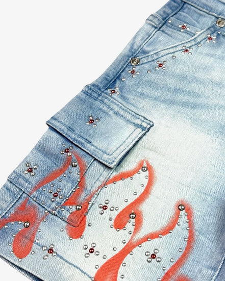 Blue jeans with red flame designs and silver studs on a white background