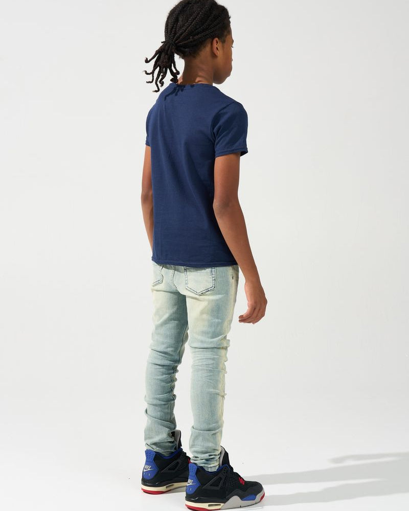 Person wearing a navy blue t-shirt, light blue jeans, and black sneakers on a white background
