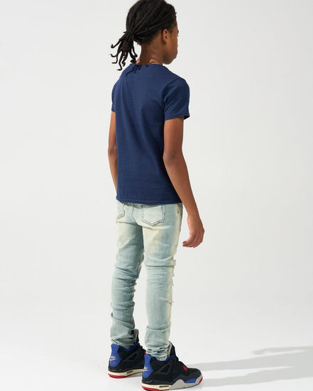 Person wearing a navy blue t-shirt, light blue jeans, and black sneakers on a white background