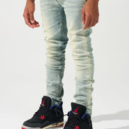 Person wearing light blue jeans and black sneakers with red and blue accents on a white background