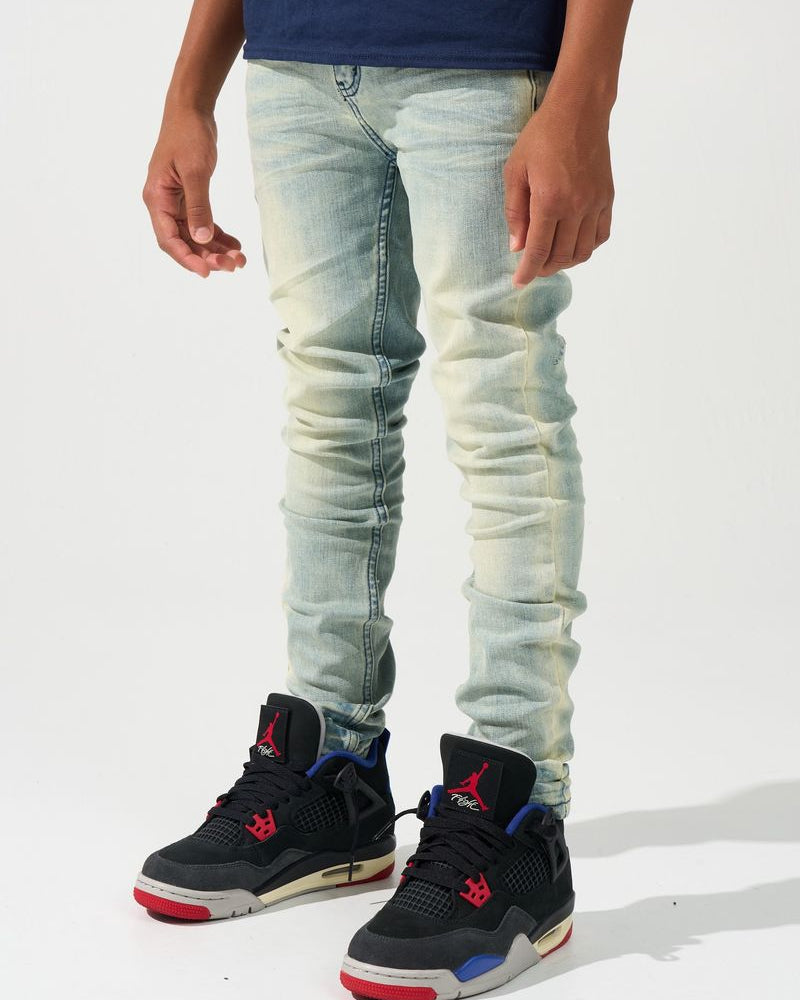 Person wearing light blue jeans and black sneakers with red and blue accents on a white background