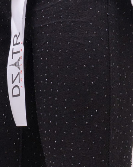 Black pants with white polka dots and a visible brand label on a black background