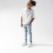 Child wearing a white t-shirt and light blue jeans on a white background