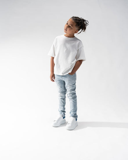 Child wearing a white t-shirt and light blue jeans on a white background
