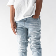 Person wearing light blue jeans and a white t-shirt on a plain background