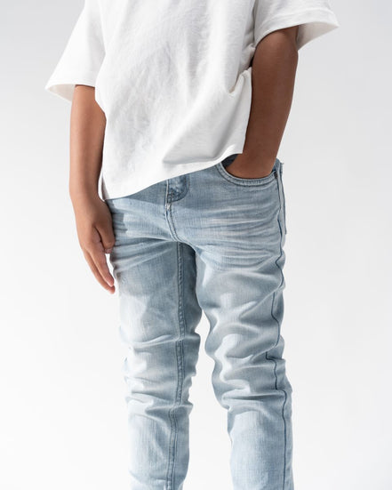 Person wearing light blue jeans and a white t-shirt on a plain background
