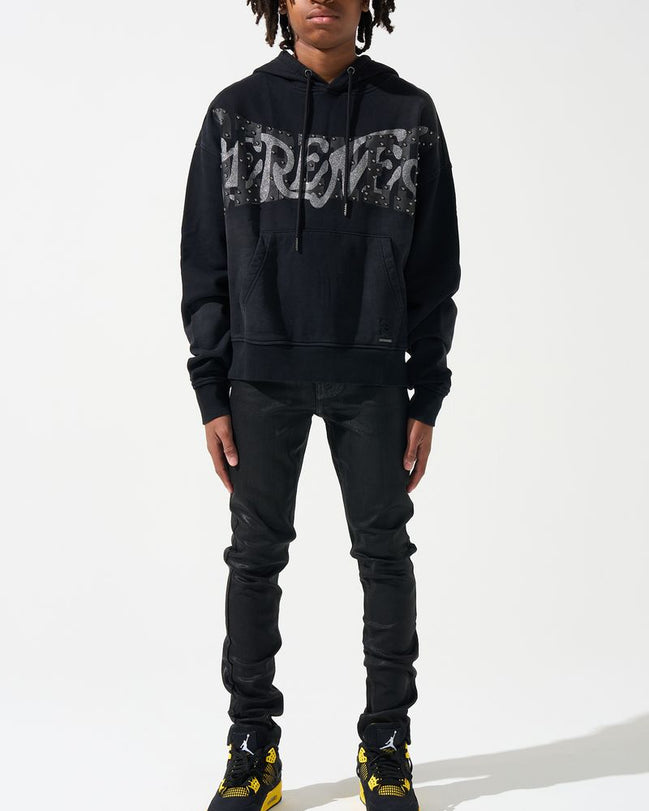 Person wearing a black hoodie with text, black pants, and black shoes with yellow accents on a white background