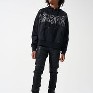 Person wearing a black hoodie with graphic design, black leather pants, and black shoes with yellow accents on a white background.