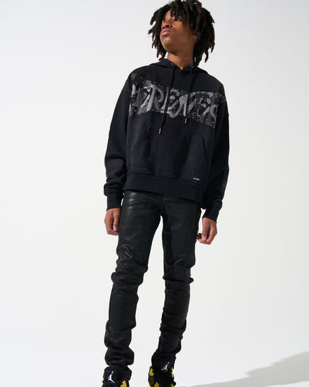 Person wearing a black hoodie with graphic design, black leather pants, and black shoes with yellow accents on a white background.