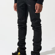 Person wearing black pants and black sneakers with yellow accents on a white background