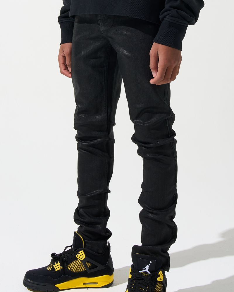 Person wearing black pants and black sneakers with yellow accents on a white background