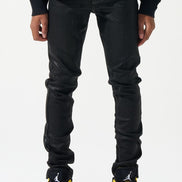 Person wearing black jeans and black sneakers with yellow accents on a white background