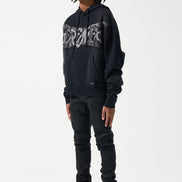 Person wearing a black Supreme hoodie and black pants with yellow accents on a white background