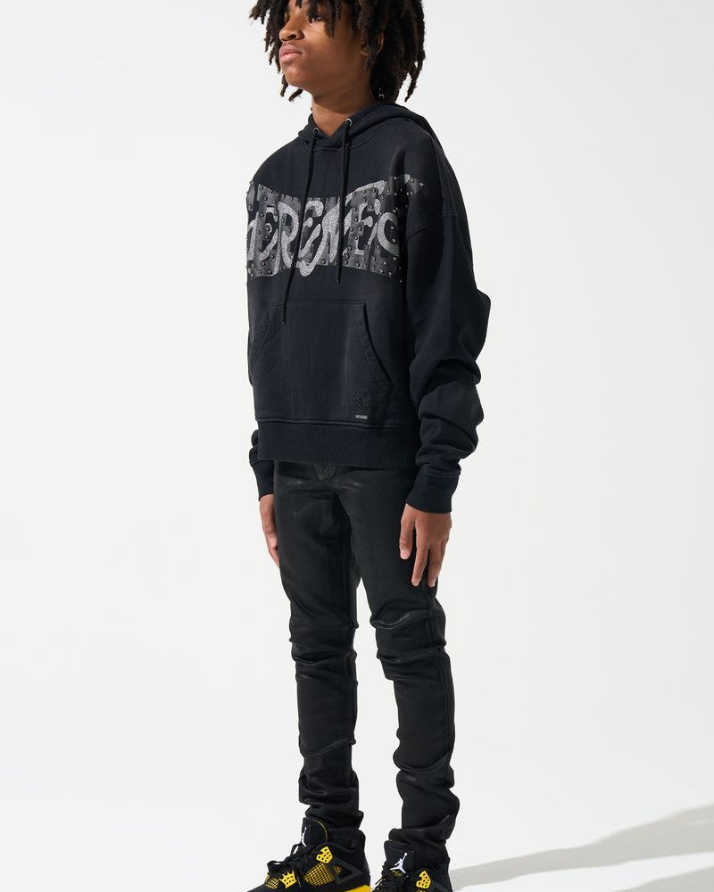 Person wearing a black Supreme hoodie and black pants with yellow accents on a white background