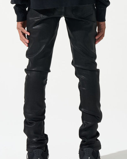 Person wearing black leather pants and black sneakers with yellow accents on a white background