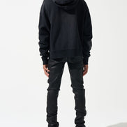 Person wearing a black hoodie and pants with a white background