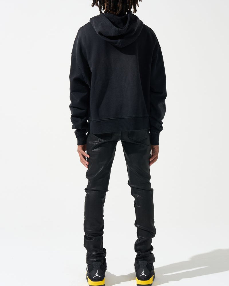 Person wearing a black hoodie and pants with a white background