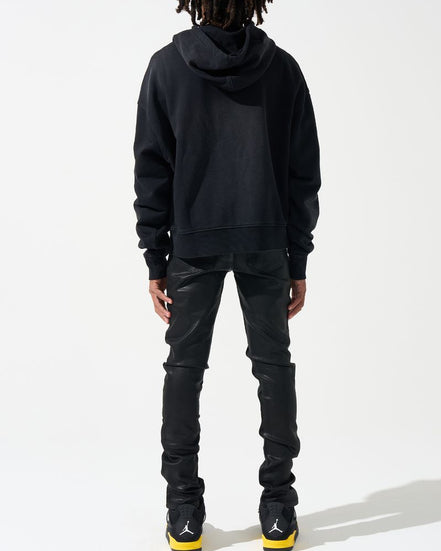 Person wearing a black hoodie and pants with a white background
