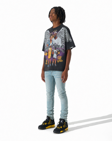 A person modeling a black graphic t-shirt with a Los Angeles Lakers print, paired with light-wash blue jeans and black and yellow sneakers, standing against a white studio background.