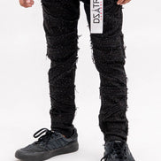 Person wearing black distressed jeans with a visible brand label on a white background